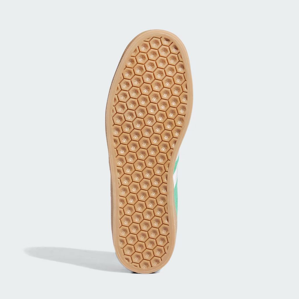 The ADIDAS GAZELLE ADV in GREEN/CLOUD WHITE/GOLD METALLIC features a tan sole with a honeycomb pattern and a premium pigskin suede upper, ensuring sleek style and durability.