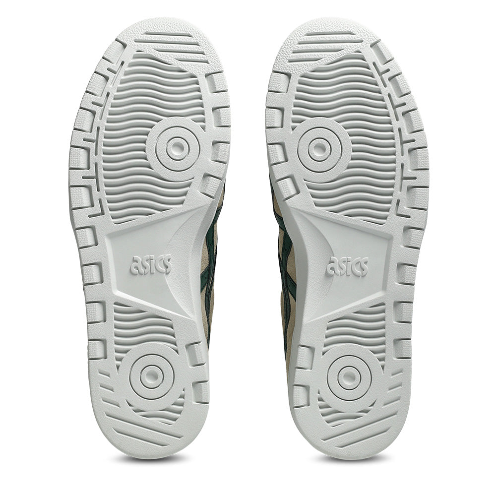 The image displays the white rubber soles of ASICS JAPAN PRO WOOD CREPE / EVERGREEN shoes, featuring circular and linear tread patterns with the ASICS logo embossed at the center of each sole.