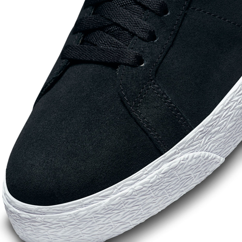 Close-up of a black nike NIKE SB BLAZER MID BLACK / WHITE sneaker with white rubber sole and black laces, highlighting the texture of the material and stitching details. This skateboarding shoe features Zoom Air cushioning for enhanced comfort.