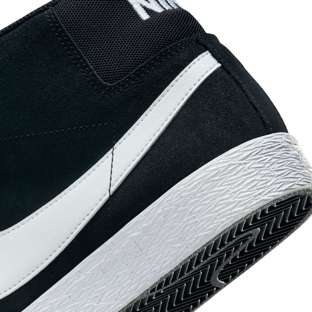 Close-up of a nike NIKE SB BLAZER MID BLACK / WHITE sneaker showing the heel and part of the sole. A white swoosh logo and textured pattern on the rubber sole are visible, perfect for skateboarding with Zoom Air cushioning for added comfort.