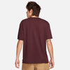 The back view of a man wearing a maroon NIKE SB LOGO SKATE TEE BURGUNDY CRUSH.