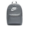 The NIKE HERITAGE BACKPACK in Smoke Grey/White, made from recycled polyester, features a white logo, front zippered pocket, top handle, and laptop sleeve.