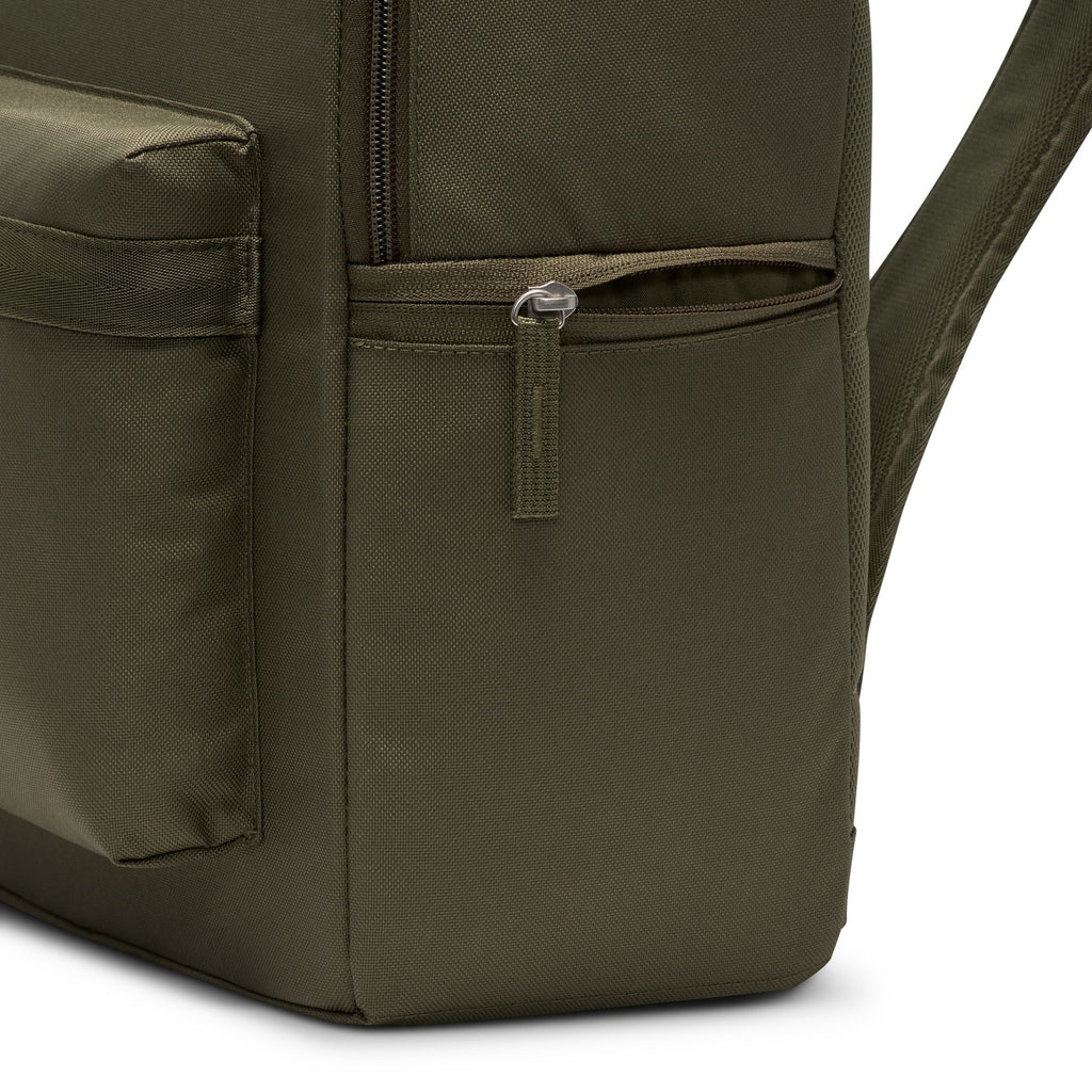 Close-up of the bottom corner of a nike HERITAGE BACKPACK MEDIUM OLIVE, crafted from recycled polyester, highlighting a zippered pocket and part of the front pocket.