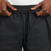A close up of a person's hands holding his Nike SB Skyring Skate Short Loose Fit Black pants.