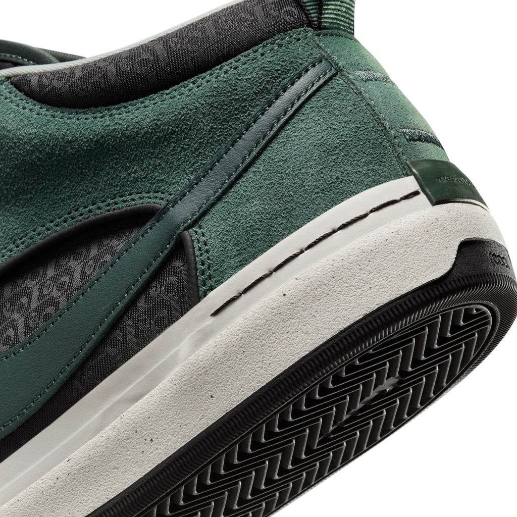 Close-up of the NIKE SB REACT LEO VINTAGE GREEN / BLACK sneaker by Nike, showcasing textured suede and a rubber sole with a herringbone pattern, finished with intricate stitching details on the heel.