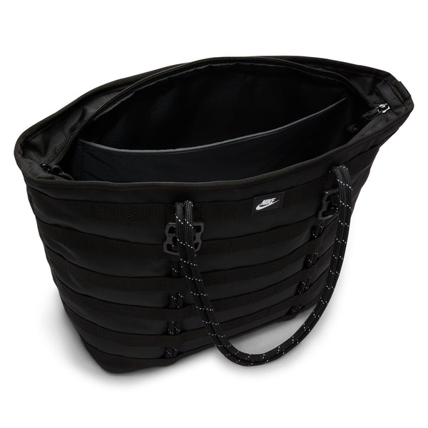 The NIKE RPM TOTE (26L) BLACK features a zippered main compartment, black webbing details, rope-style handles, and a small Nike logo—ideal as a laptop bag or an everyday tote made from recycled polyester.