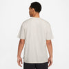 The back view of a man wearing a nike SB 'SPORTS GUY' SKATE TEE LIGHT BONE t-shirt in beige.