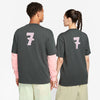 Two people showing the back of a faded black tshirt with a pink number 7 on it.