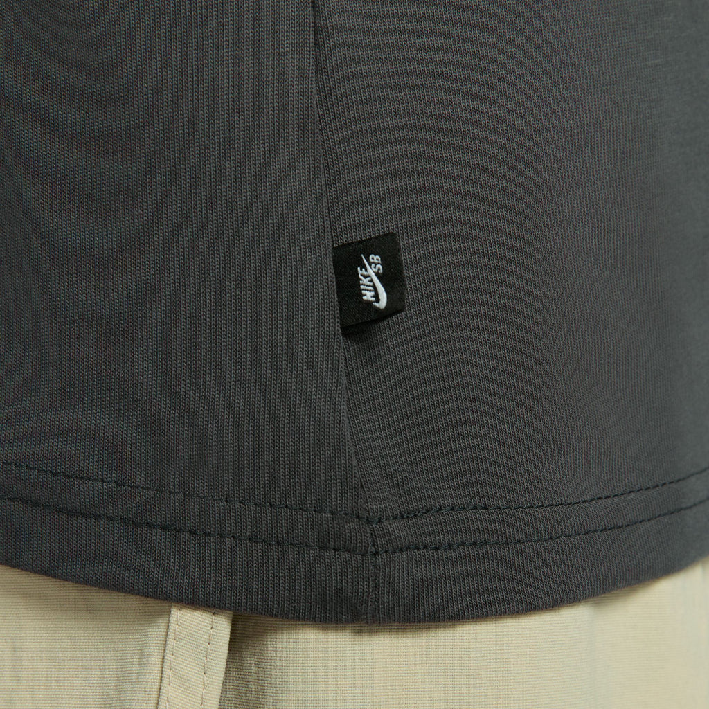 An up close of a small black nike sb logo tag sewn into the side of a faded black shirt.
