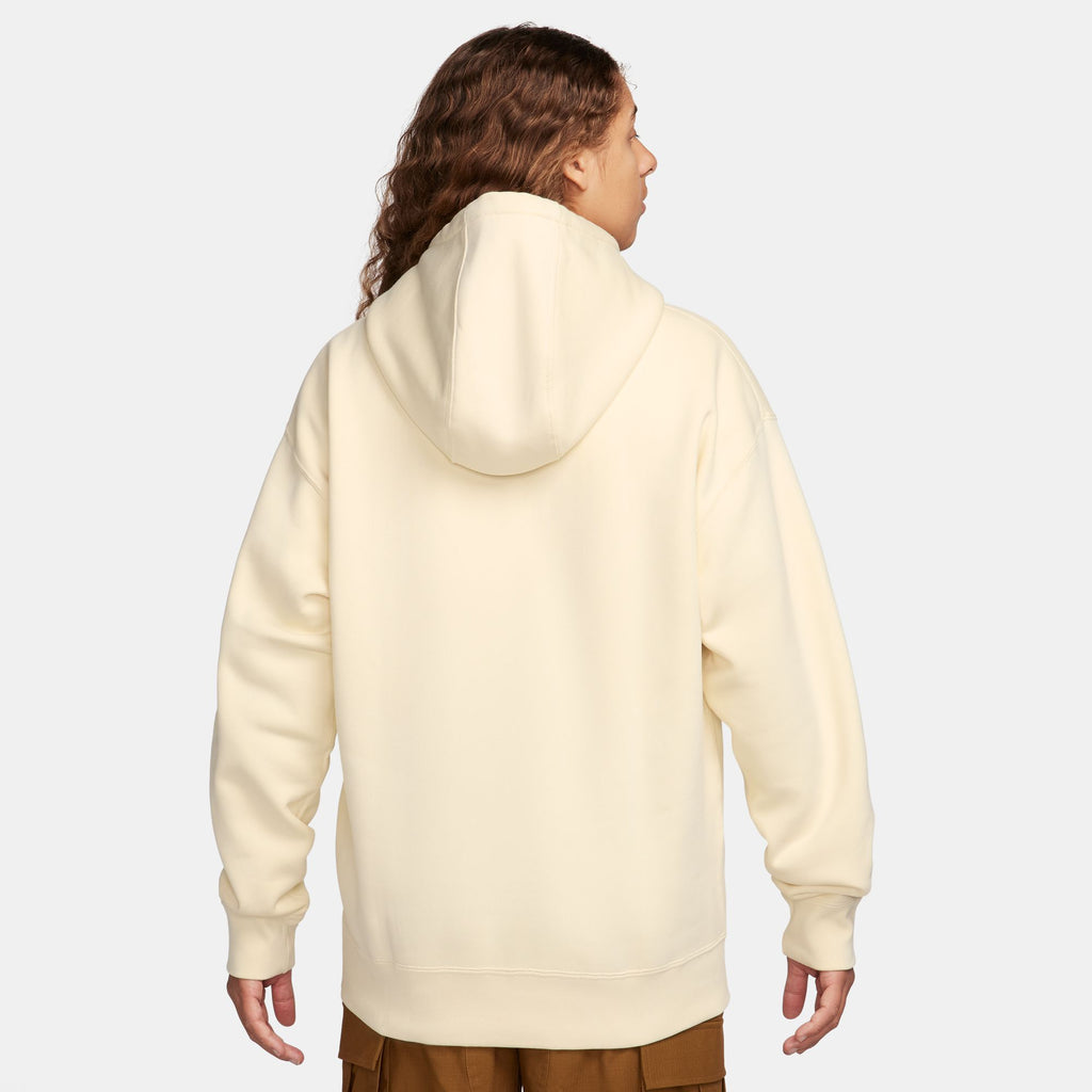 The back view of a woman wearing a nike SB 'City of Love' fleece hoodie in coconut milk.