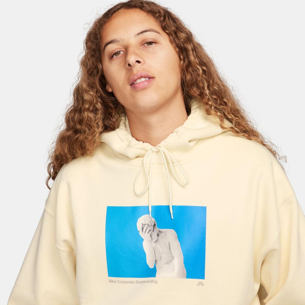 A woman wearing a yellow NIKE SB 'CITY OF LOVE' FLEECE HOODIE COCONUT MILK with a photo of a woman.
