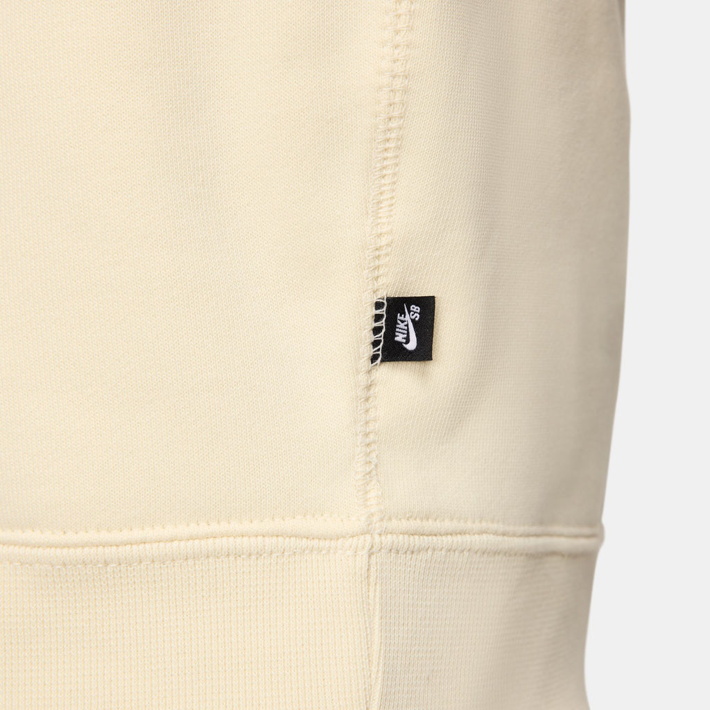 A close up of a white NIKE SB 'CITY OF LOVE' FLEECE HOODIE COCONUT MILK with a black nike logo on it, featuring the SEO keyword "NIKE SB".