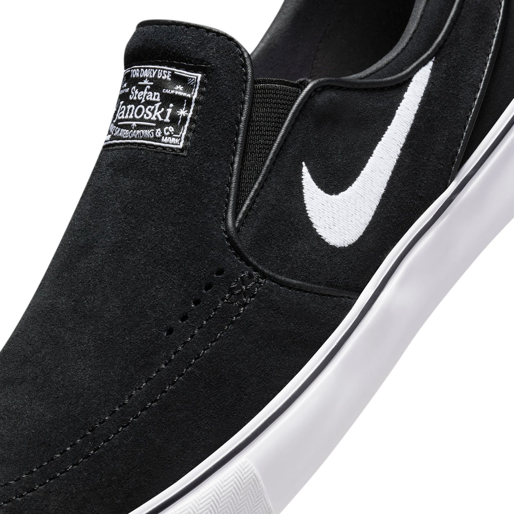 Close-up of the NIKE SB JANOSKI+ SLIP in black, showcasing a white swoosh, tongue label, and thick white sole. Features Zoom Air cushioning and skate-specific tread for optimal performance.