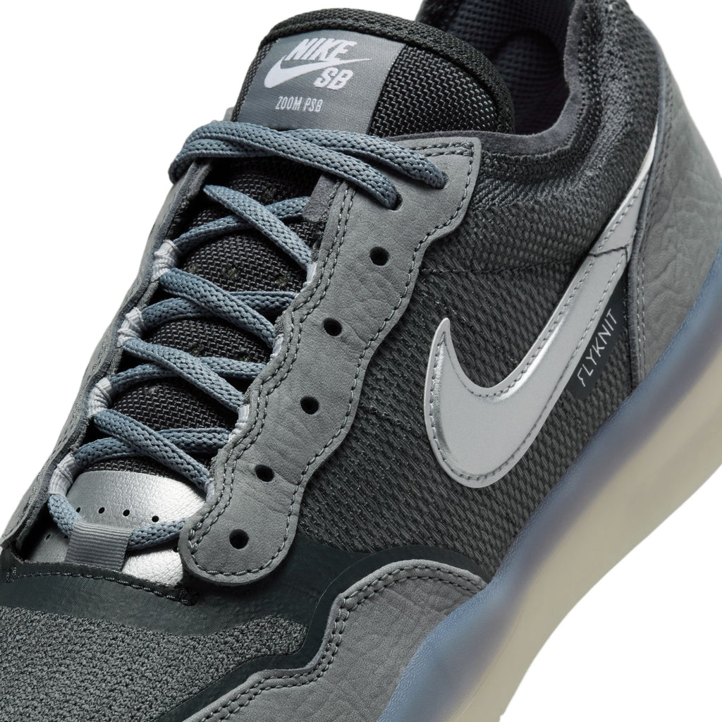 Close-up of a NIKE SB PS8 COOL GREY / METALLIC SILVER sneaker by Nike, showcasing a textured mesh design, Flyknit construction, and Air Zoom cushioning for enhanced comfort.