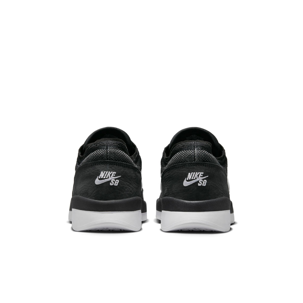 Back view of NIKE SB PS8 BLACK / WHITE sneakers featuring Flyknit construction and white soles, against a plain backdrop.