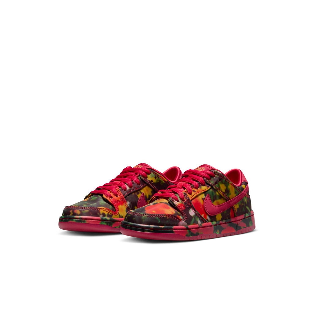 NIKE SB DUNK LOW sneakers for little kids feature a vibrant camo pattern in red, yellow, and green with a striking red swoosh and matching laces. Perfect for budding skateboarders who love bold style. Set against a plain white background, these sneakers are from the iconic brand Nike.