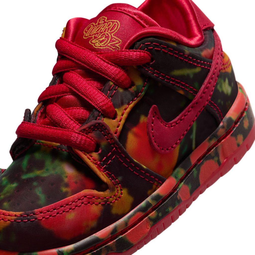 The NIKE SB DUNK LOW TODDLER sneaker from Nike sports a red and black tie-dye pattern, bold red laces, and a striking red swoosh logo, perfect for stylish toddlers ready to skateboard.