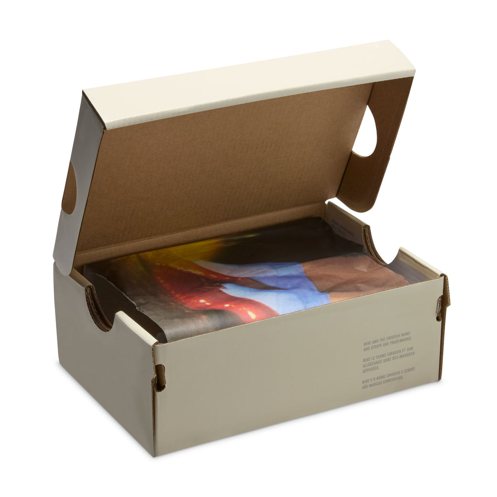 An open shoe box reveals a folded, colorful printed shirt inside, echoing the vibrant style of the NIKE SB DUNK LOW 👠💚 TODDLER sneakers by Nike.