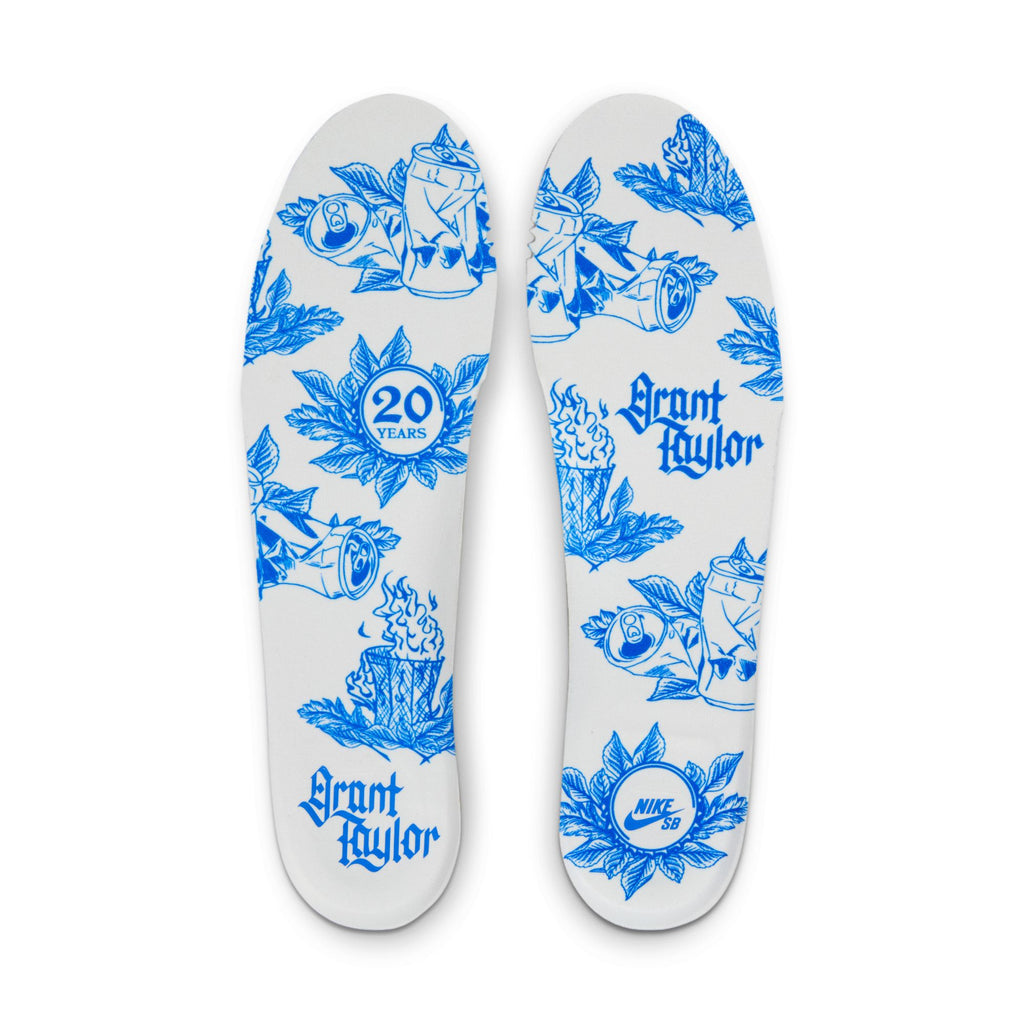 The insoles of the NIKE SB BLAZER LOW PRO GT "20 YEARS" SUMMIT WHITE/GAME ROYAL showcase blue illustrations, including a "20 Years" badge and "Grant Taylor." With Air Zoom cushioning, these insoles provide comfort ideal for skaters.