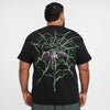 A man with curly hair is turned away, wearing the NIKE SB SPIDER TEE BLACK GLOW IN THE DARK by Nike, which showcases a vibrant green and purple graphic design featuring "Nike SB" and "NBA", blending camo elements into its artwork.