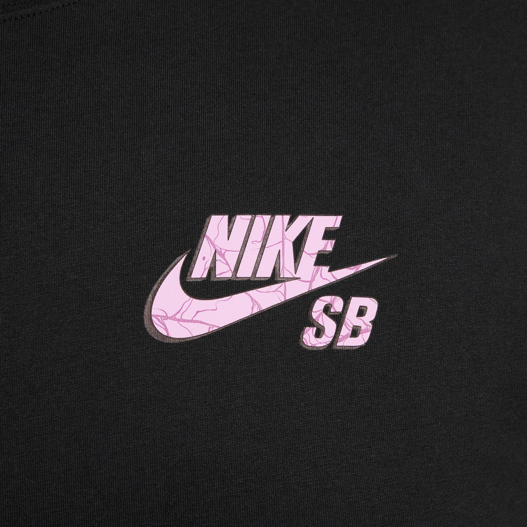 NIKE SB SPIDER TEE BLACK GLOW IN THE DARK featuring the iconic Nike logo in a textured pink pattern on a black shirt, set against a camo-inspired background.