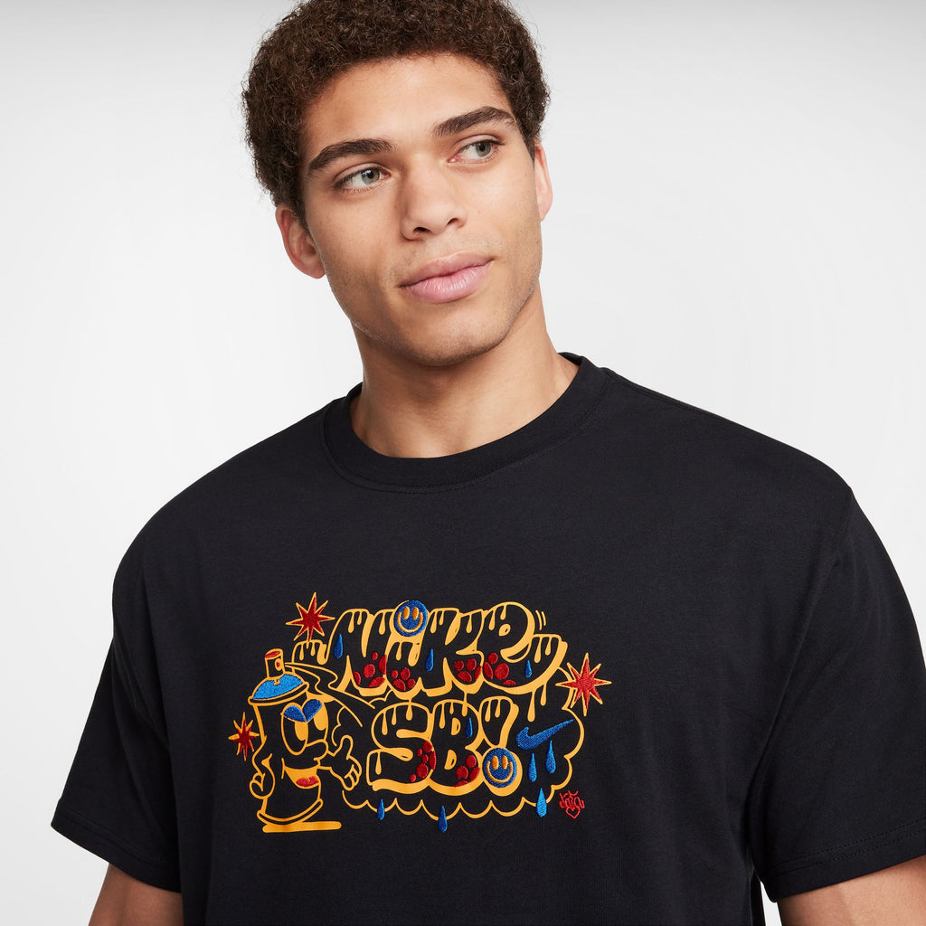 Person wearing a NIKE SB Max90 Spray Can Skate Tee in black with colorful graphic text.