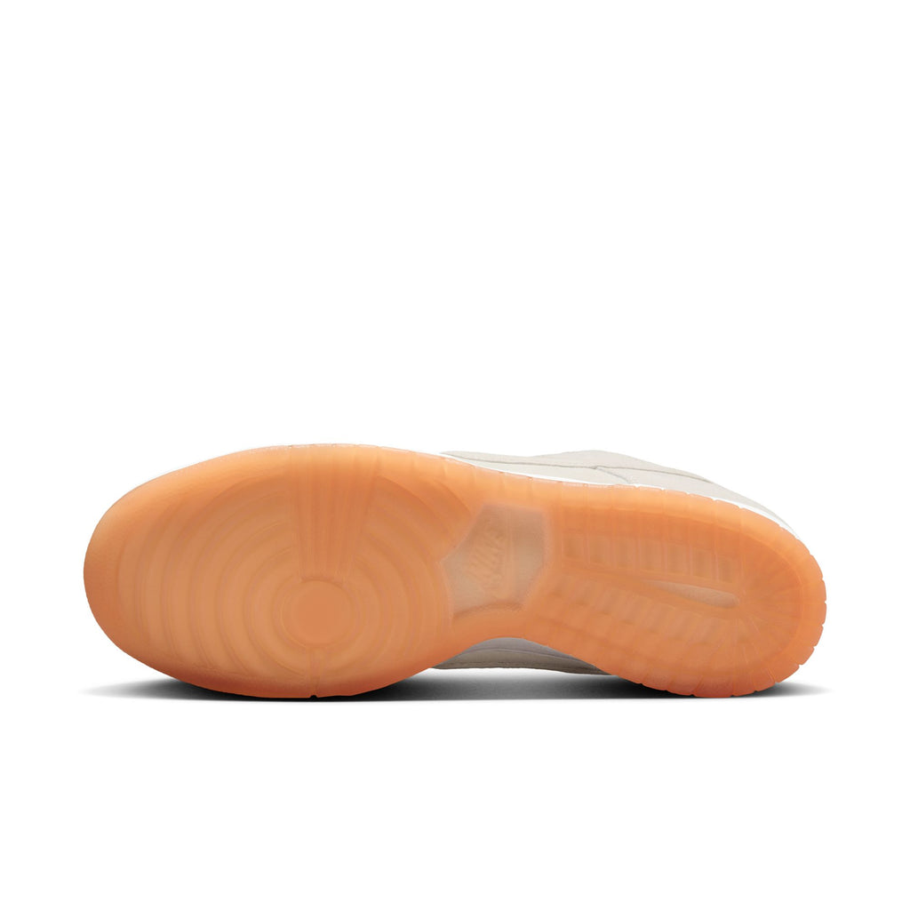 The image shows the bottom view of the NIKE SB DUNK LOW PRO B PALE IVORY / SUMMIT WHITE by nike, featuring a textured, translucent orange rubber sole.