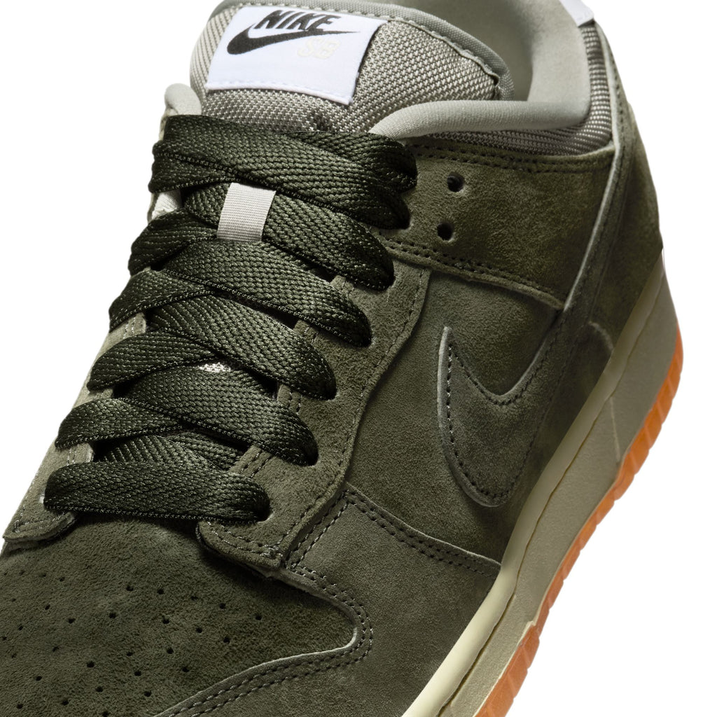 Close-up of a nike SB Dunk Low Pro B in Sequoia/Light Army-White, featuring olive green suede, dark green laces, a white tongue label, and a gum-colored sole.