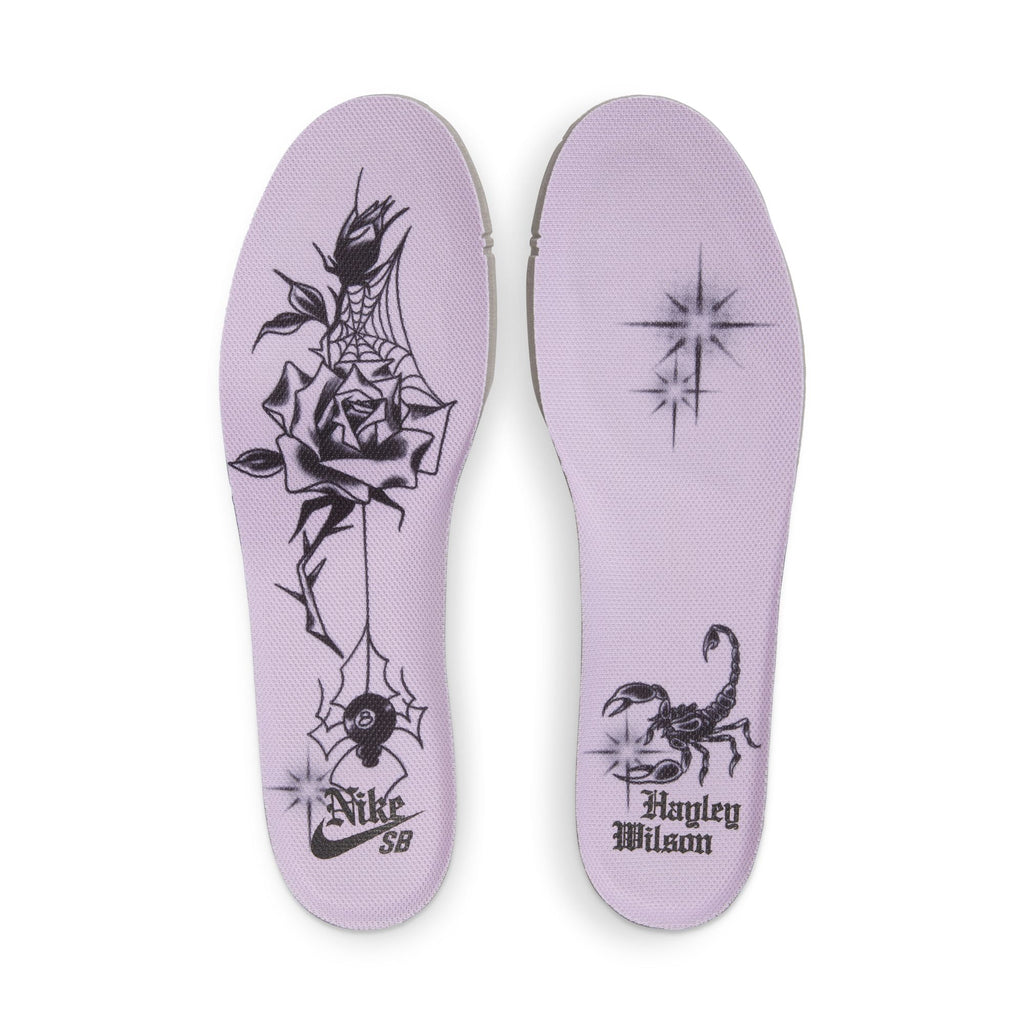 The Nike SB Hayley Wilson Dunk Low Pro in Court Purple/Black-White-Lagoon Pulse features lavender insoles with black tattoo-style graphics: a rose and spiderwebs on the left, scorpion and "Hayley Wilson" on the right, all with lightweight cushioning.