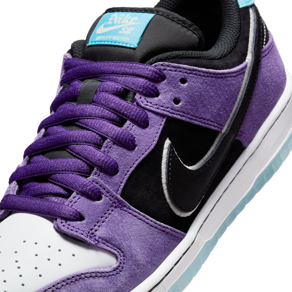 A close-up of the NIKE SB Hayley Wilson Dunk Low Pro highlights court purple suede overlays, black accents, a white toe box, and lagoon pulse details on the tongue and heel tab.