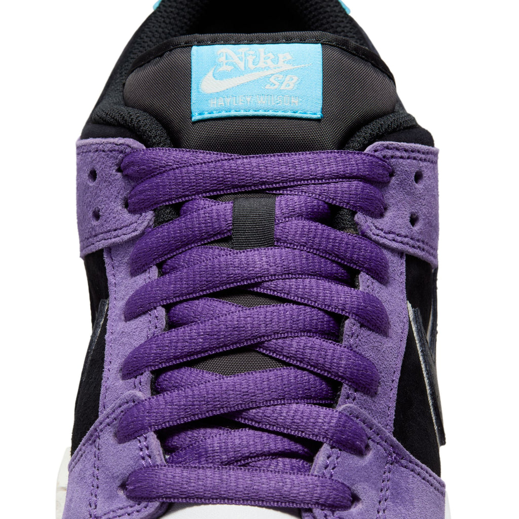 Close-up of the nike SB Hayley Wilson Dunk Low Pro in Court Purple/Black-White-Lagoon Pulse, featuring purple laces, a black tongue, blue logo label, and premium materials for comfort and style.