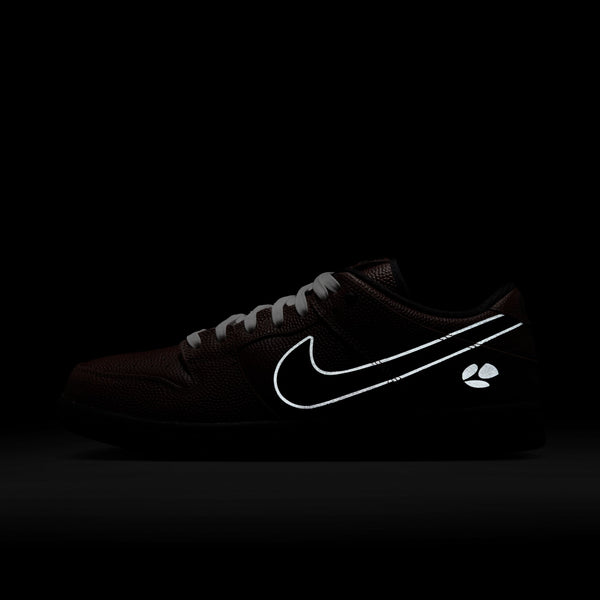 The nike SB x Limo Dunk Low Pro in Dark Pony/Black-Silver-White features football-textured black leather, a reflective white Swoosh, and a small reflective logo near the heel, shown against a dark background.