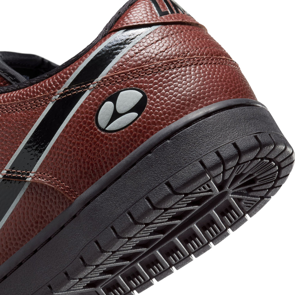 Close-up of the heel and sole of the NIKE SB x Limo Dunk Low Pro (Dark Pony/Black-Silver-White) with custom laces, football-textured leather, a black and white stripe, and a black and white circular logo.