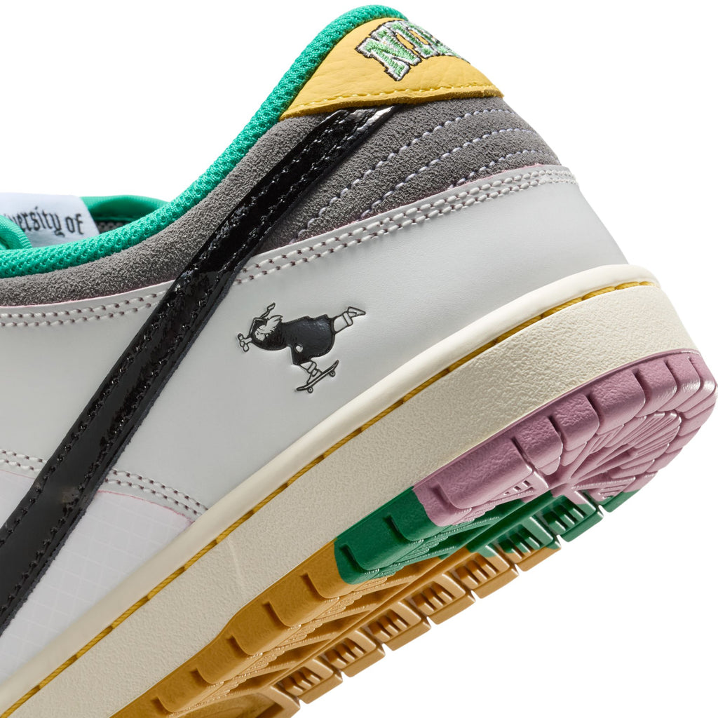 Close-up of the NIKE SB x CSEF Dunk Low in Summit White/Black-White-Iron Grey by nike, featuring colorful accents, a small black cartoon skateboarding character, and a glossy patent leather Swoosh on the side.