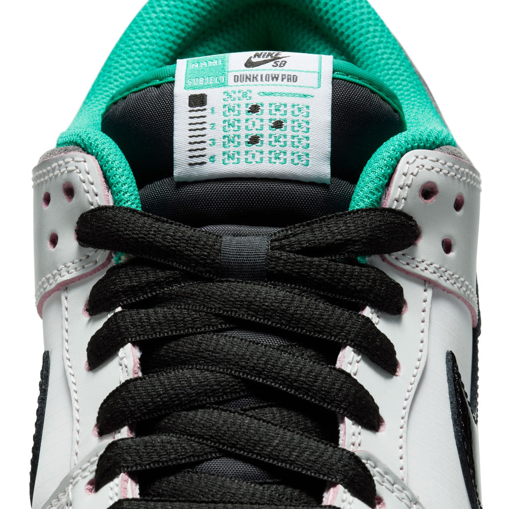 Close-up of the nike NIKE SB X CSEF DUNK LOW SUMMIT WHITE / BLACK-WHITE-IRON GREY, showing its College Skateboarding Educational Foundation tongue label, black laces, white leather upper with green lining, and shiny patent leather Swoosh.