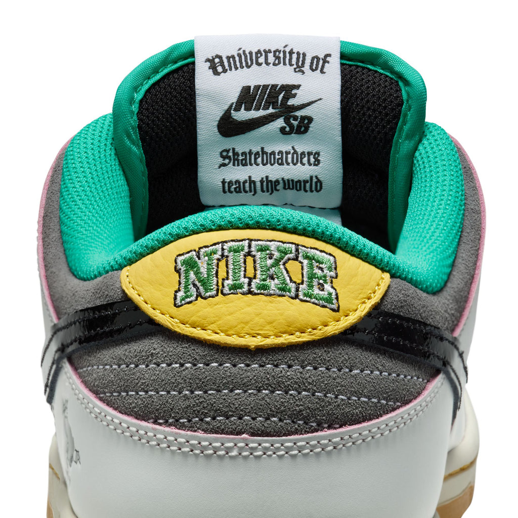 Close-up of the nike SB x CSEF Dunk Low in Summit White/Black-White-Iron Grey, highlighting its teal lining, yellow and green "NIKE" embroidery, visible tongue label, and glossy patent leather Swoosh—styled for the College Skateboarding Educational Foundation.