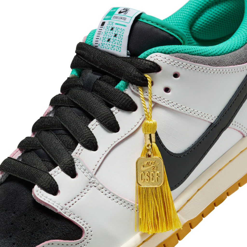 Close-up of the nike SB x CSEF Dunk Low in Summit White/Black-White-Iron Grey, featuring a gold tassel and CSEF tag on the laces, highlighting its skateboarding scholarship connection.