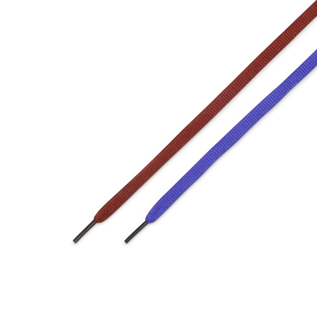 A red and a blue shoelace, inspired by the NIKE SB DUNK LOW PRO PERSIAN VIOLET / OFF NOIR from nike, lie side by side on a white background, their aglets pointing outward—a vibrant nod to Bluetile Skateboards style.