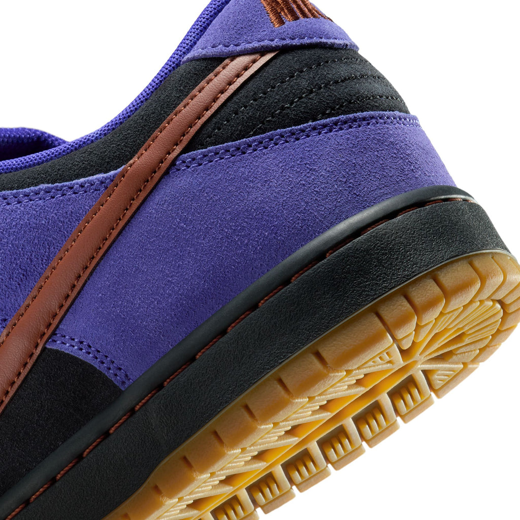 Close-up of the heel of the NIKE SB DUNK LOW PRO PERSIAN VIOLET / OFF NOIR by nike, showing purple suede, black and brown accents, and a textured yellow rubber outsole—an exclusive from Bluetile Skateboards.