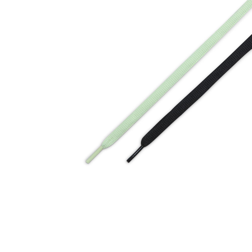 A pair of shoelaces—one light green, one black—are displayed side by side, perfect for customizing your nike NIKE SB DUNK LOW PRO VERDUGO MOUNTAIN before your next ride.