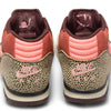 A pair of NIKE SB X ARTS-REC AIR TRAINER 1 shoes in Limestone/Pink Quartz with animal print on the heel, pink swooshes, and printed insoles are viewed from the back.