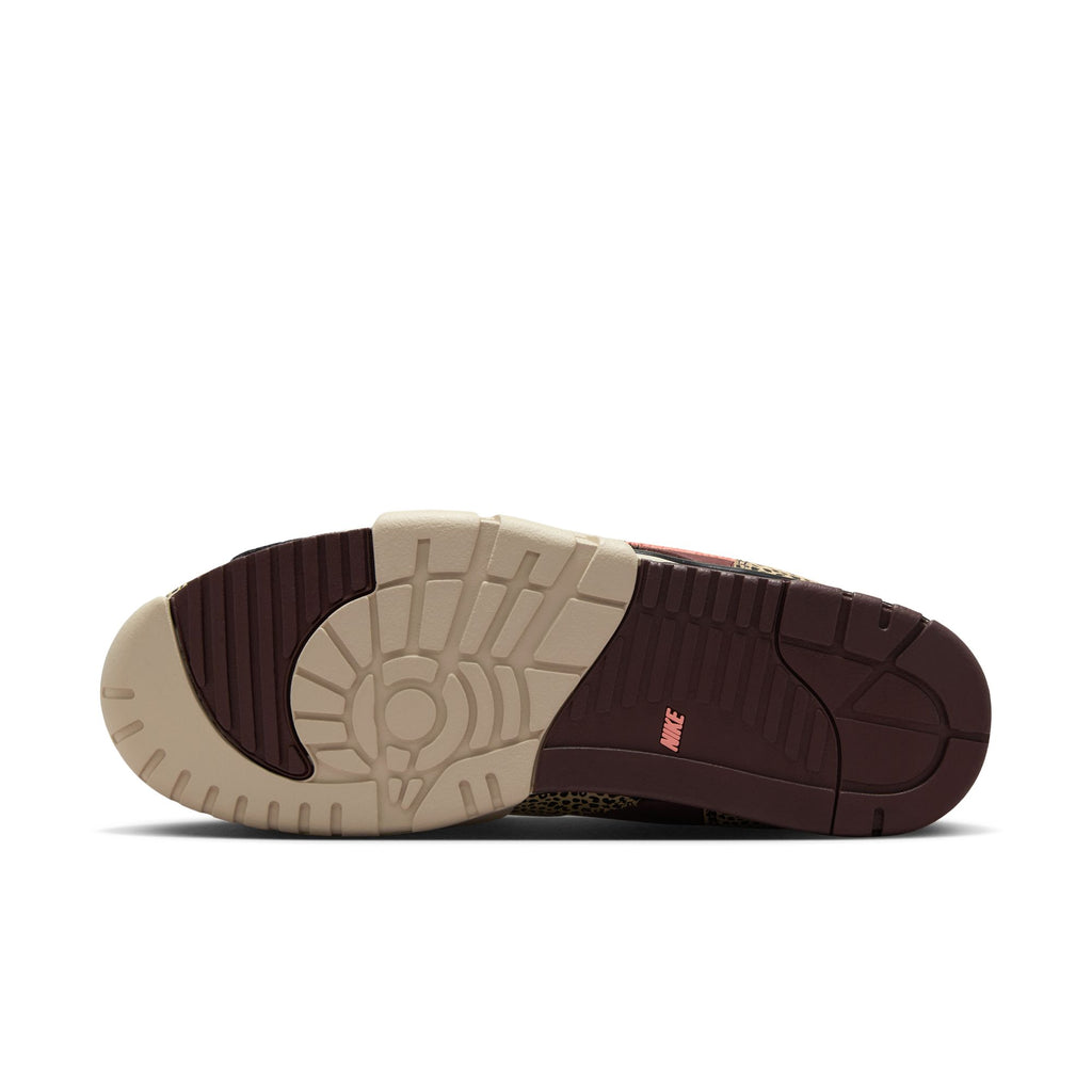 The image displays the outsole of the NIKE SB x ARTS-REC AIR TRAINER 1 in Limestone/Pink Quartz-Earth-Dusty Peach-Black-Desert Sand, featuring patterned beige and dark brown rubber with a pink Nike logo—ideal for skateboarding fans.