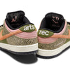 A pair of Nike SB x Arts-Rec Dunk Low Pro sneakers in khaki, amber brown, rough green, rust pink, black, and sail with "arts" on the left heel and "rec" on the right. Features animal print details and coral swooshes.