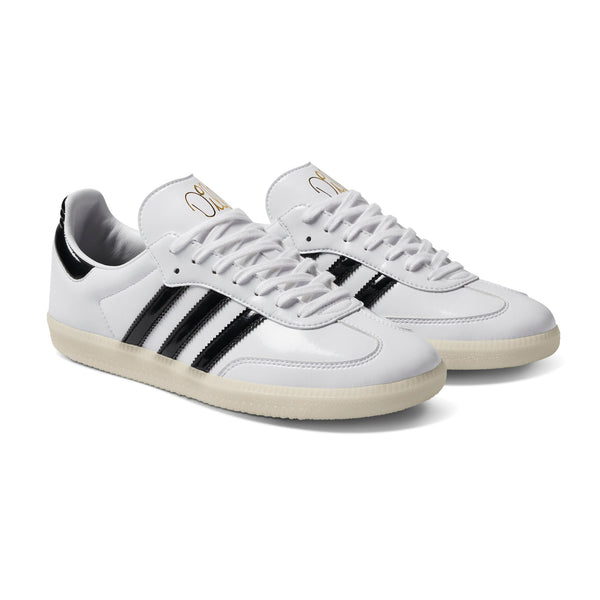 A white and black ADIDAS DILL SAMBA PATENT sneakers with stripes.