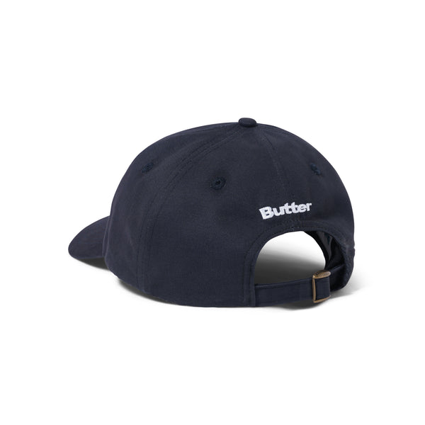 A navy Butter Goods baseball cap with the word 'buffer' embroidered on it, featuring a washed navy color and canvas patchwork 6 panel design.