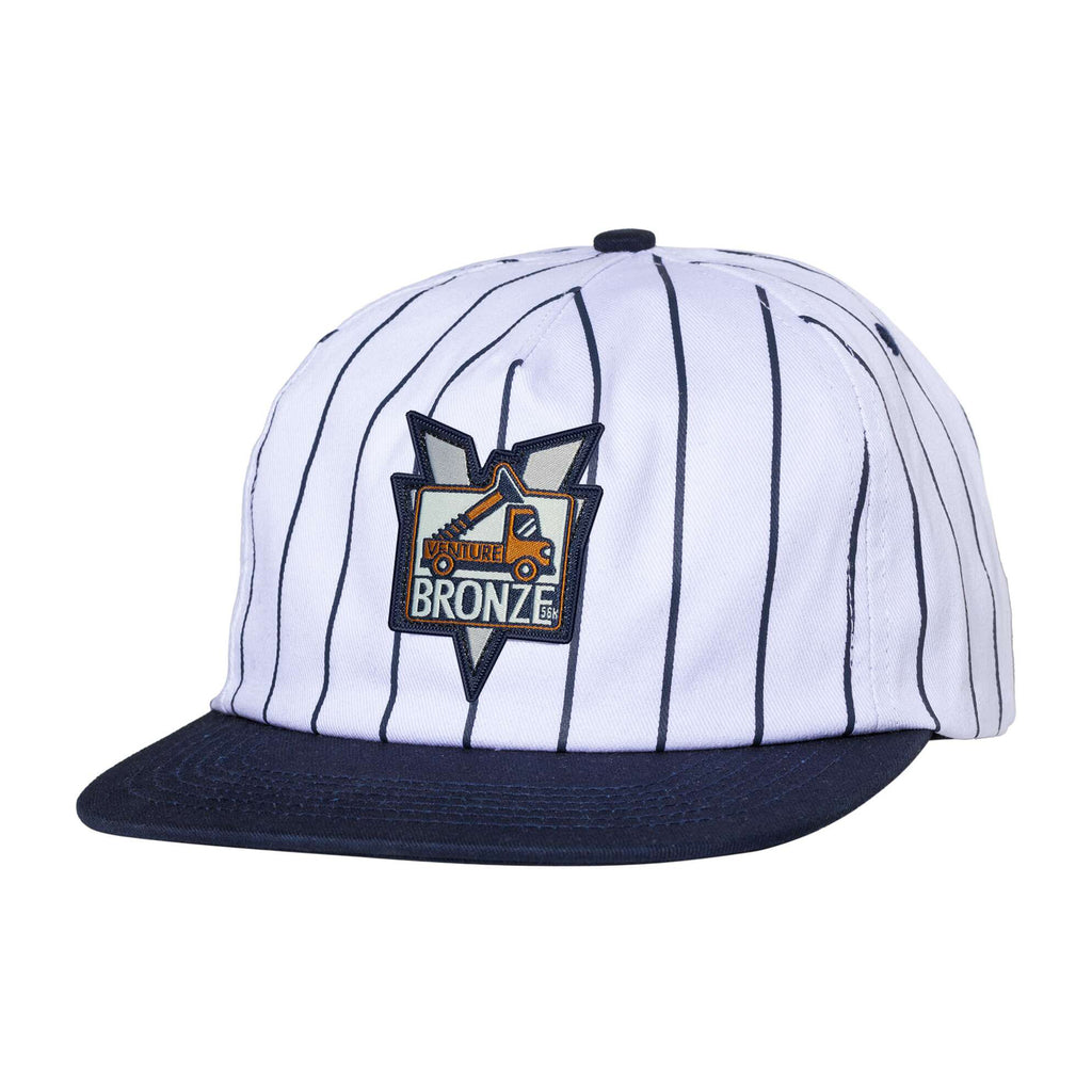 The VENTURE X BRONZE 56K PINSTRIPE HAT by Carpet Co. features a white design with black pinstripes and a flat navy brim, highlighted by a colorful embroidered "BRONZE" logo on the front. This hat combines classic style with modern flair in true Carpet Cowboy fashion.