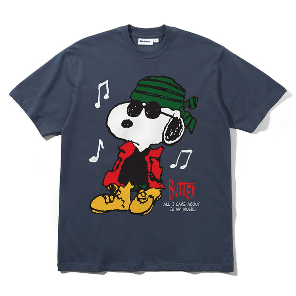 The Butter Goods x Peanuts Music Tee Slate is a navy 100% cotton T-shirt with Snoopy in sunglasses, green bandana, red jacket, yellow boots, music notes, and “BUTTER” & “ALL I CARE ABOUT IS MY MUSIC!” on the front—a classic Butter Goods piece.