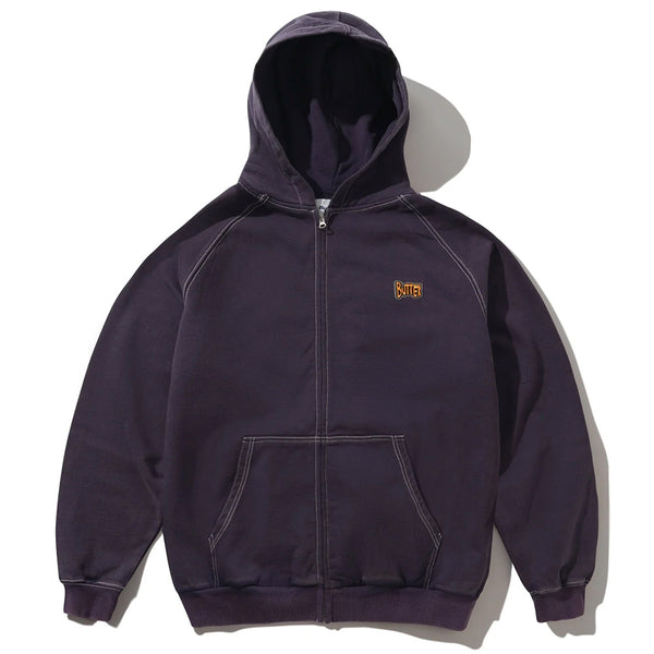 The Butter Goods BUTTER SKETCH ZIP-THRU HOODIE EGGPLANT is a dark purple hoodie featuring a front pocket, hood, and a small embroidered yellow and red logo patch on the left chest.