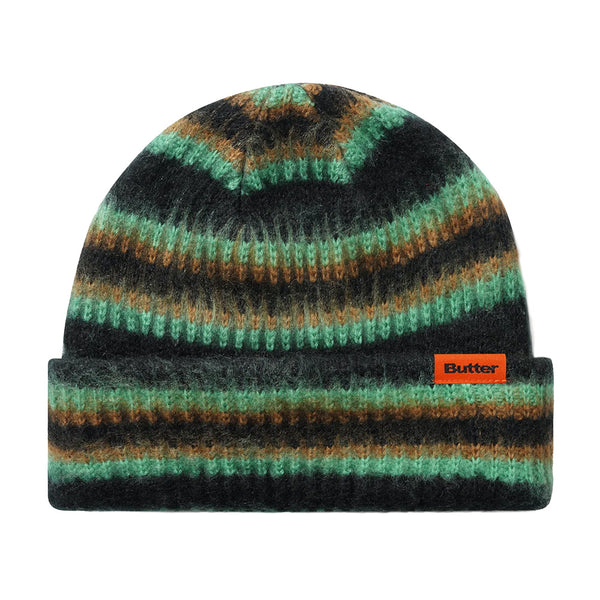 The Butter Goods BUTTER SWIPE BEANIE BLACK features jacquard green, brown, and black stripes, a folded brim, and an orange "Butter" label on the front.