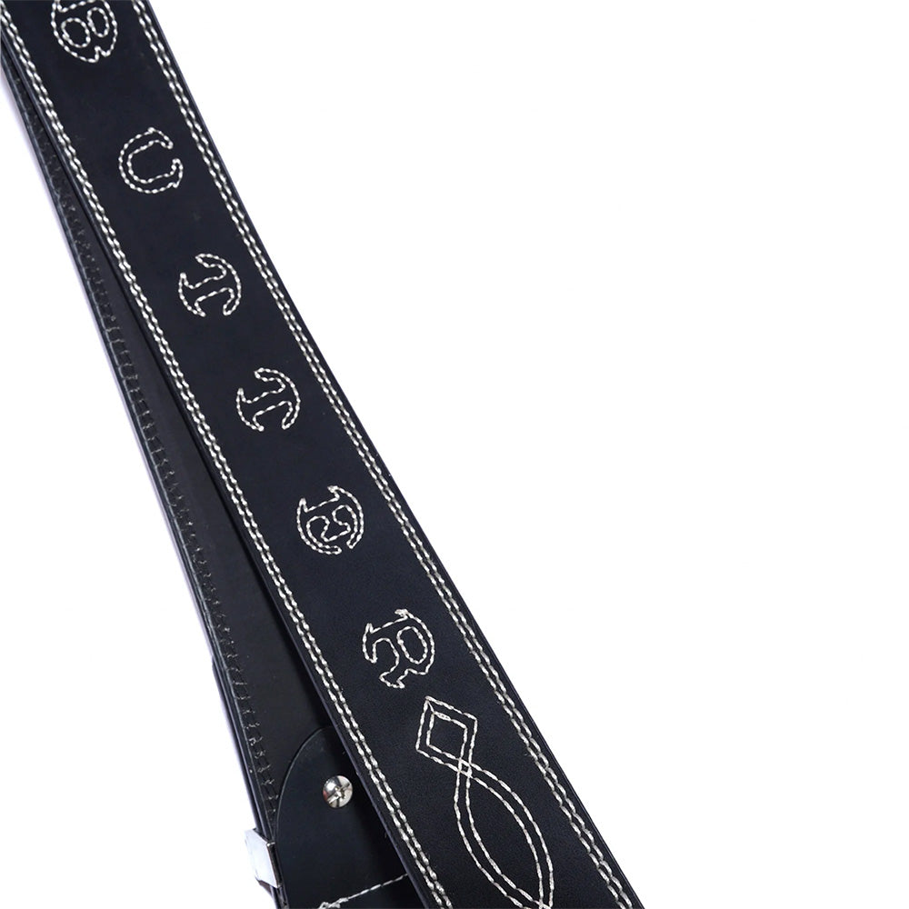 A close-up of the BUTTER BRONCO BELT BLACK by Butter Goods, a black leather belt featuring contrast stitching and white stitched designs, including a treble clef and other unique symbols.